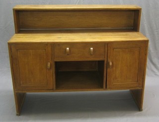 An Art Deco oak sideboard with raised back fitted 1 long drawer above a niche flanked by a pair of cupboards by Heal 51"