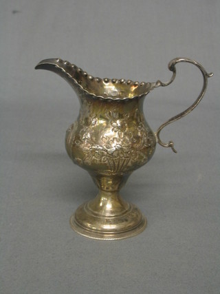 A Georgian embossed silver cream jug raised on a circular spreading foot, London 1776, 2 ozs