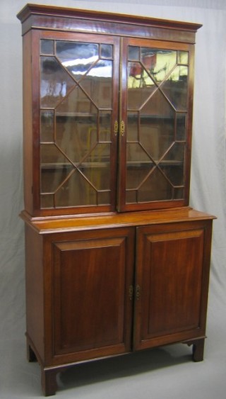 A 19th Century mahogany bookcase on cabinet, the upper section with moulded cornice, the interior fitted adjustable shelves enclosed by astragal glazed panelled doors, the base fitted a cupboard enclosed by panelled doors, raised on bracket feet 42"
