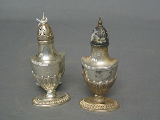 A pair of Victorian oval silver pepperettes with armorial and demi-reeded decoration, London 1897