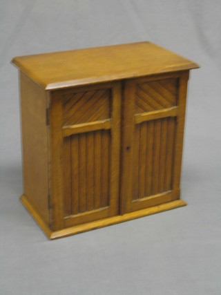 A honey oak aesthetic movement table top cabinet enclosed by panelled doors, the interior fitted 3 drawers 13"