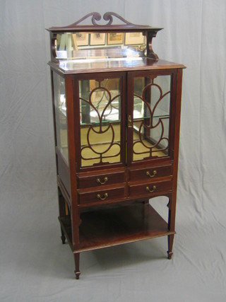 An Edwardian mahogany display/music cabinet the upper section with mirrored back, the interior fitted adjustable shelves enclosed by glazed panelled doors, the base fitted 2 long drawers above undertier, raised on square tapering supports 29"