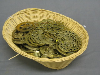 An oval basket containing various modern horse brasses