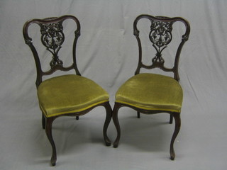 A pair of Edwardian mahogany dining chairs with pierced shaped backs and upholstered seats raised on cabriole supports