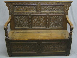 A Victorian carved oak settle with hinged lid, carved throughout 60"