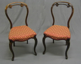 A pair of Victorian pierced rosewood balloon back dining chairs, the seats of serpentine outline and raised on French cabriole supports