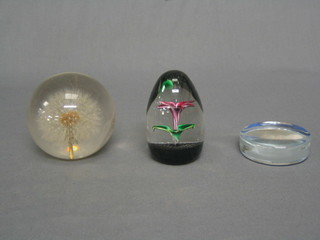 A circular glass paperweight decorated a photograph of a Hovercraft, a plastic paperweight with daisy head and a Strathearn paperweight (3)