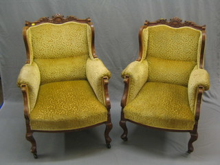 A pair of Edwardian carved walnut show frame wing armchairs upholstered in yellow material and raised on cabriole supports