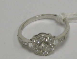 A lady's Art Deco style dress ring set a diamond shaped diamond supported by 8 diamonds and with 4 baguette cut diamonds to the shoulders (approx 0.48ct)