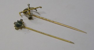 A gold stick pin in the form of a hunting horn with horse shoe and 2 crossed whips and 1 other stick pin