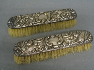 A pair of embossed silver backed clothes brushes (some holes)