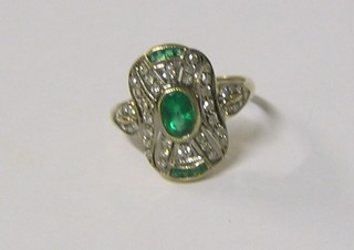 A lady's 18ct gold dress ring set an oval emerald  supported by 8 emeralds and numerous diamonds (approx 0.70ct)