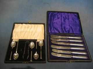 A set of 5 silver plated coffee spoons with matching tongs, cased and a set of 6 silver handled tea knives
