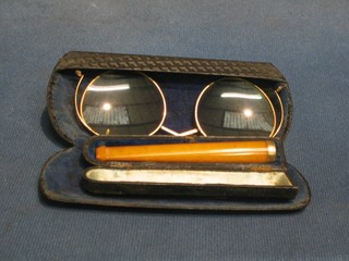 An amber cheroot holder and a pair of gilt metal spectacles