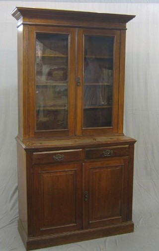 A Victorian walnut bookcase on cabinet, the upper section with moulded cornice, the interior fitted adjustable shelves enclosed by glazed panelled doors, the base fitted 2 drawers above double cupboard, raised on a platform base 42"