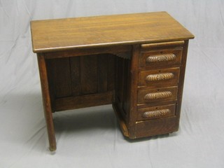 An Edwardian oak typists desk fitted a brushing slide above 4 long drawers, 34"