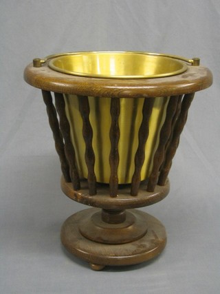 A circular oak waste paper basket holder with bobbin turned decoration and brass liner and brass swing handle 14"