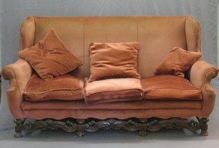 A William & Mary style oak framed winged back sofa, upholstered pink material 67"