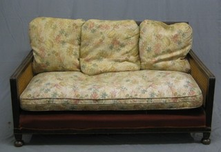 A 1930's oak framed and double caned 3 piece bergere suite with 3 seat settee, 2 matching armchairs and floral patterned loose cushions