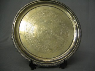 A circular engraved silver plated salver, raised on 3 ball and claw supports 12"