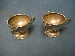 A pair of circular 3 handled salts, raised on spreading feet (marks rubbed)