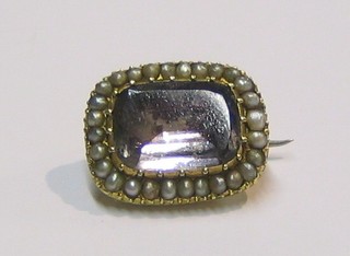 A 19th Century gold bar brooch set an oval foil backed stone surrounded by demi-pearls