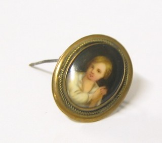 An oval porcelain and enamelled brooch in the form of a seated boy contained in gilt metal mounts