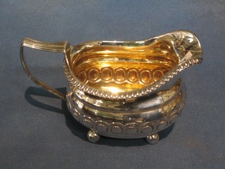 A George III silver cream jug with gadrooned border, embossing to the body, raised on 4 bun feet 6 ozs