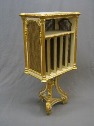 A 19th Century French white painted and gilt banded rectangular revolving folio stand with double cane panels, raised on a triangular base 24"