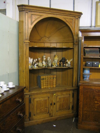 A handsome Georgian pine corner cupboard with moulded and dentil cornice, fitted 3 shelves, the base fitted a double cupboard, raised on a platform base 61"