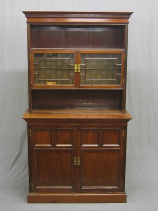 An Edwardian walnut bookcase on cabinet, the upper section with moulded and dentil cornice fitted a niche above a cupboard enclosed by astragal glazed panelled doors, the base fitted a niche above cupboards enclosed by panelled doors, raised on bracket feet 39"