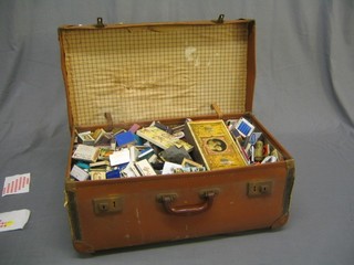 A collection of match box labels contained in a 1950's fibre suitcase complete with hotel and other labels to the exterior