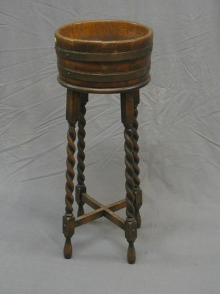 A 1930's circular oak coopered jardiniere stand raised on spiral turned supports with X framed stretcher 13"