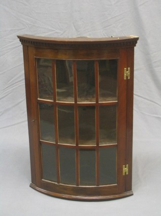 A 20th Century Georgian style mahogany hanging corner cabinet with moulded and dentil cornice, the interior fitted shelves enclosed by a  glazed panelled door 22"