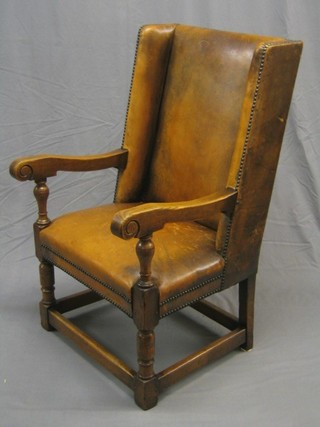 A 1930's wing back oak open arm chair raised on turned and block supports