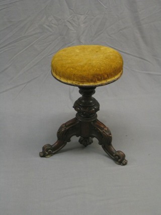 A Victorian carved walnut adjustable piano stool raised on a tripod base