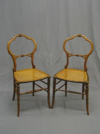 A pair of Victorian carved satinwood balloon back bedroom chairs with carved mid rails and cane seats