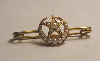 A Victorian gold bar brooch in the form of a star and crescent moon set demi-pearls