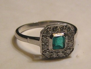 A lady's 18ct white gold dress ring set a square cut emerald surrounded by numerous diamonds