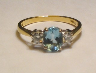 A lady's 18ct yellow and white gold dress ring set an oval cut aquamarine supported by 2 diamonds