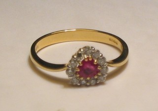 A lady's 18ct yellow gold dress ring set a heart cut ruby surrounded by diamonds