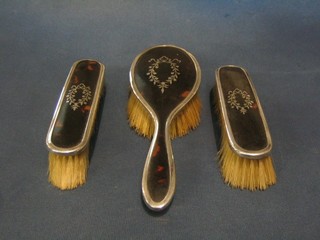 A 3 piece silver and tortoiseshell backed dressing table set with hair brush and 2 clothes brushes, Birmingham 1919