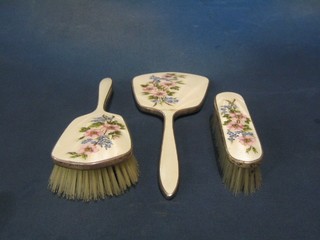 A silver plated and enamelled 3 piece dressing table set with hand mirror, hair brush and clothes brush, backed with floral decoration (hand mirror f)