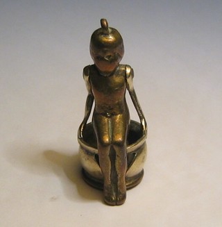 A novelty brass cigar cutter in the form of a child sitting on a chamber pot