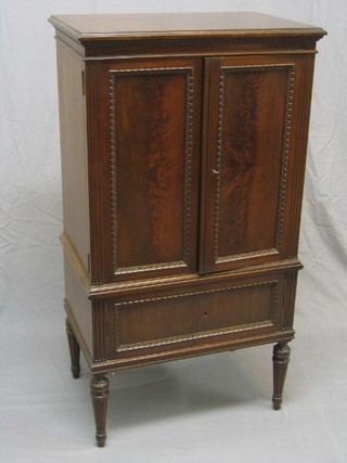 A 19th Century French mahogany music cabinet enclosed by panelled doors, raised on turned and fluted supports 26"