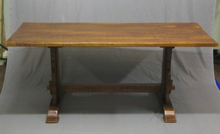 An oak refectory dining table raised on standard end supports united by an H framed stretcher 73"