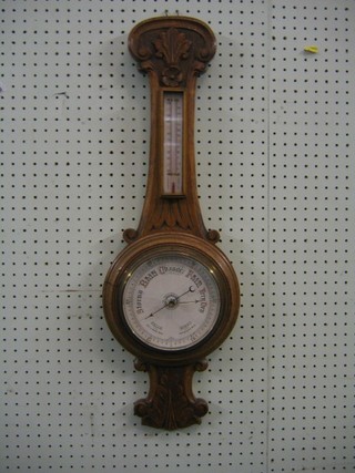An aneroid barometer and thermometer contained in a carved oak wheel case (glass f)