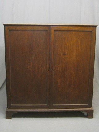 A 19th Century Country mahogany press cabinet, with crossbanded top, the interior fitted 3 trays, above 2 long drawers enclosed by panelled doors and raised on bracket feet 49"