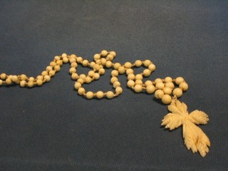 A French 19th Century carved ivory harvest festival cross hung on an ivory bead chain