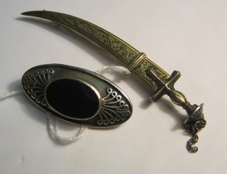 A silver brooch in the form of scimitar and 1 other brooch